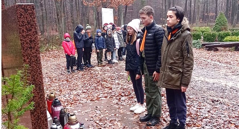 Zdjęcie przedstawia harcerzy z drużyny „Młode Wilki”, którzy oddają hołd pomordowanym mieszkańcom Królewca i Adamowa pod pomnikiem w lesie smykowskim