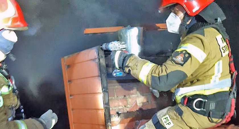 Na zdjęciu strażacy gaszą płonące sadze ze szczytu dachu