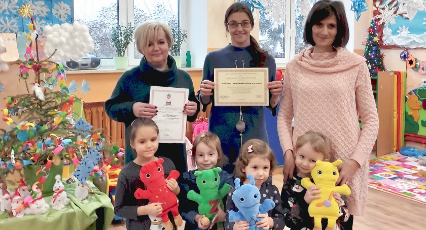 Zdjęcie przedszkolaków z Rogowa z opiekunkami, które prezentują certyfikat i zaświadczenie nauczania dwujęzycznego