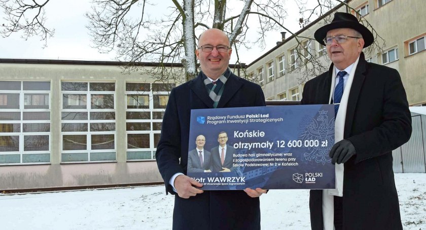 Zdjęcie Piotra Wawrzyka, wiceministra spraw zagranicznych i posła, który przekazuje burmistrzowi  Krzysztofowi Obratańskiemu symboliczny czek na budowę hali sportowej