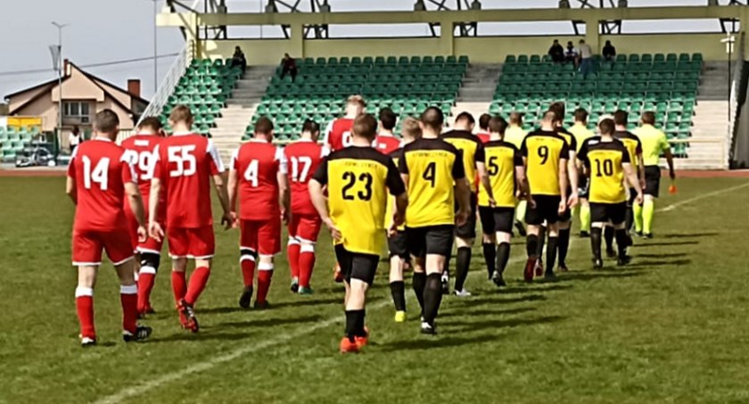 Zdjęcie drużyn Sparty Strawczynek i KS Kamienna Wola wychodzących na murawę boiska Centrum Sportowo-Rekreacyjnego w Strawczynku