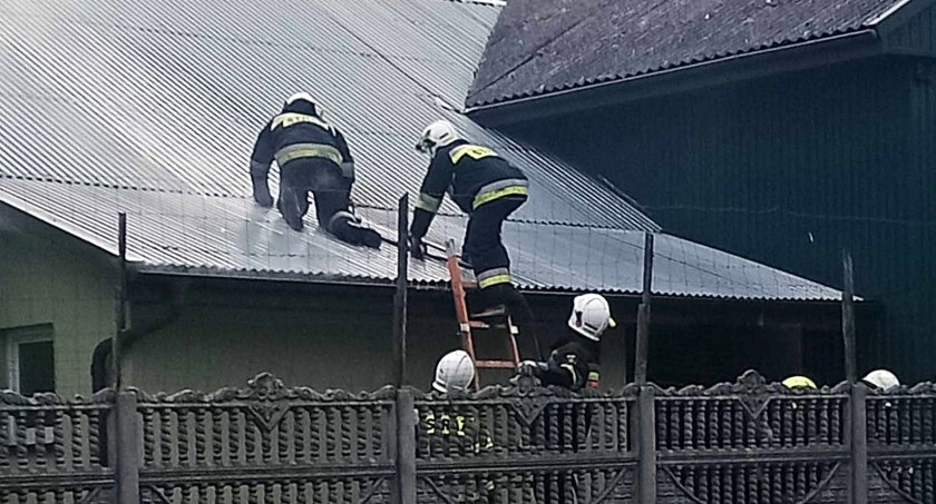 Zdjęcie strażaków, którzy wycinali dziurę w blaszanym dachu i gasili pożar