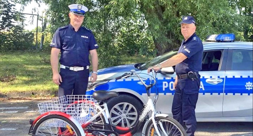 Zdjęcie podkomisarza Marcina Wąsika i asp.sztab. Stanisława Patrzykąta z trójkołowym prezentem dla 21-latki