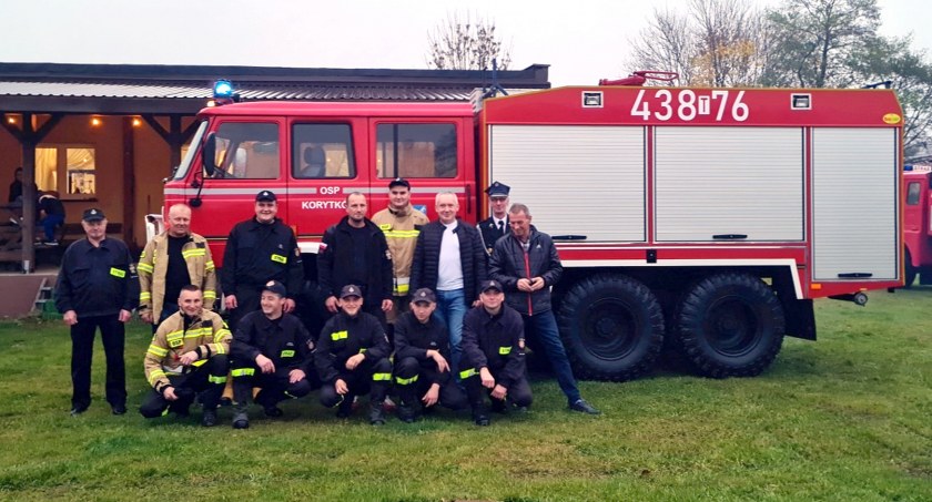 Zdjęcie nowego wozu strażackiego OSP Korytków, a na jego tle druhowie i wójt