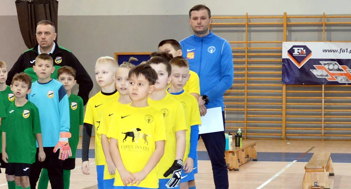 Zdjęcie zwycięskiej drużyny AP Champions Końskie (w żółtych strojach) z trenerem Adrianem Ferencem (w niebieskim dresie)