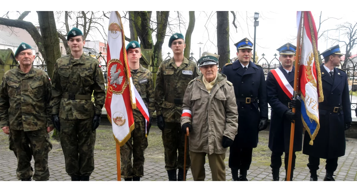 Zdjęcie mundurowych pocztów sztandarowych i kapitana Zdzisława Kowalskiego
