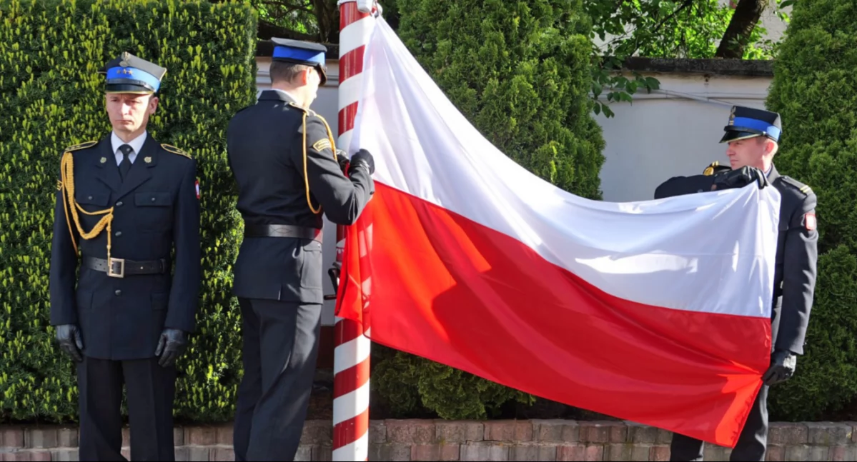 Zdjęcie strażackiego pocztu, który podnosi flagę na maszt