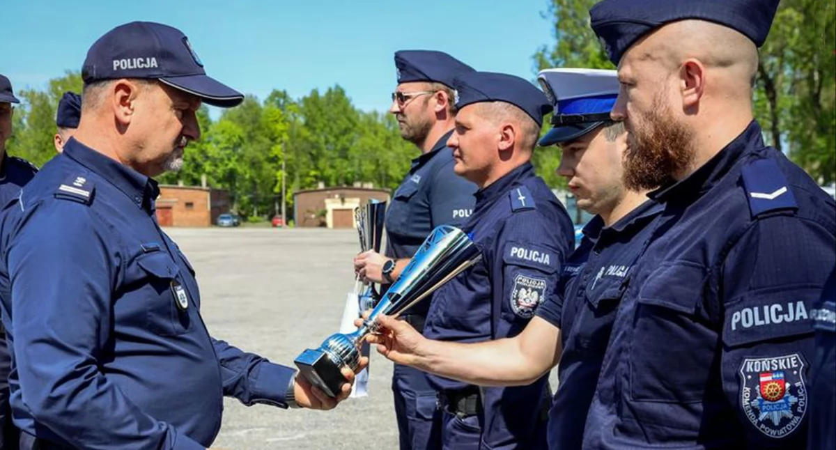 Zdjęcie zastępcy kom. woj. policji insp. Tomasza Jarosza, który wręcza puchar za drugie miejsce drużynie z Końskich w składzie sierż. szt. Michał Bernat i sierż. Michał Patrzykąt