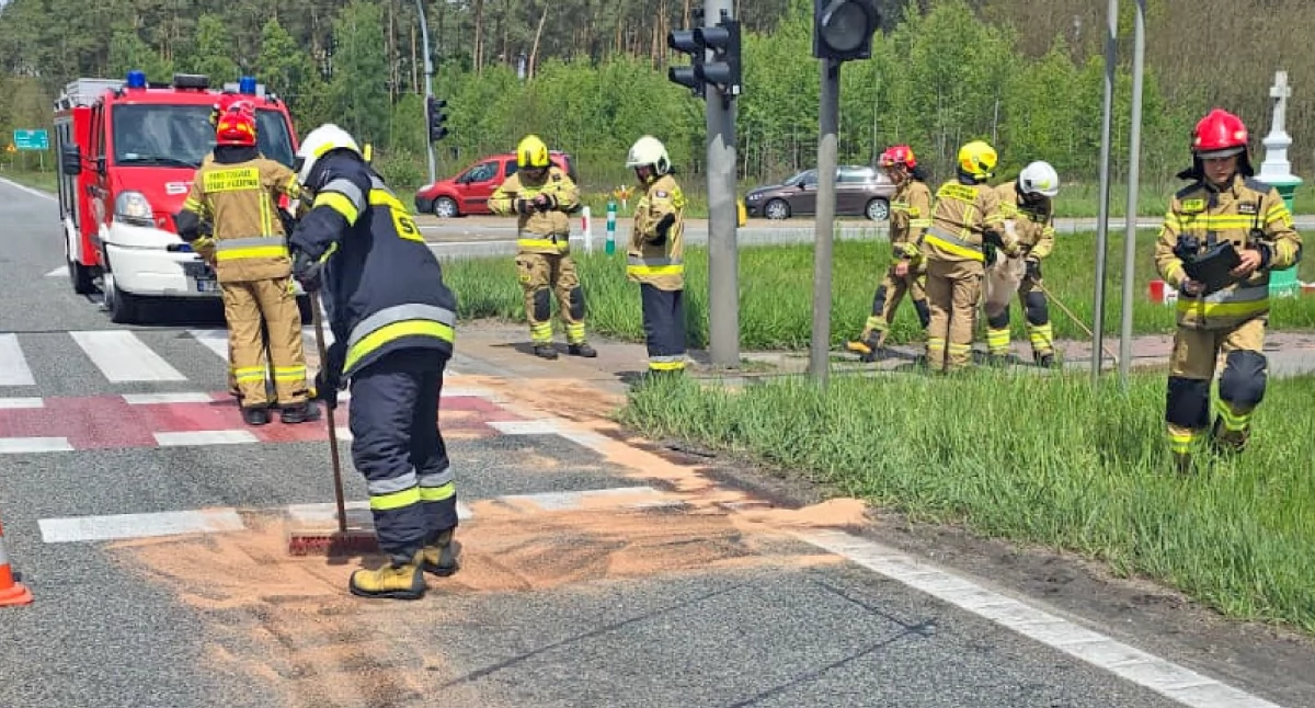 Zdjęcie strażaków sprzątających płyny pokolizyjne, jakie wylały się na jezdnię z uszkodzonych aut