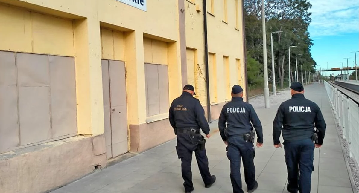 Zdjęcie funkcjonariusziy obok starego budynku dworca PKP Końskie