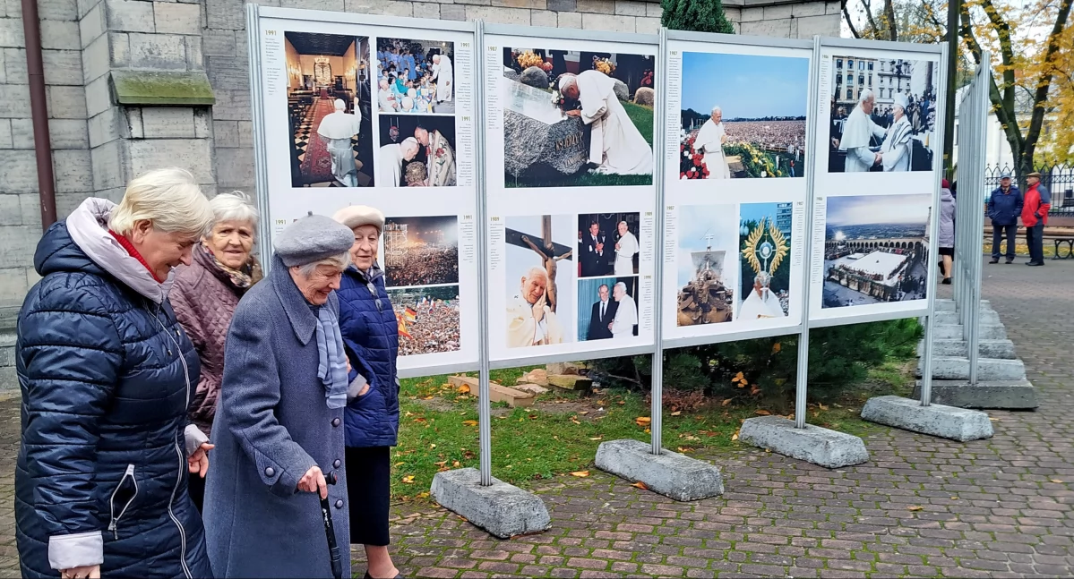 Zdjęcie zwiedzających wystawę fotografii Świętego Jana Pawła II przy koneckiej kolegiacie