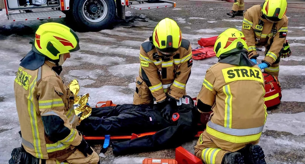 Zdjęcie strażaków, którzy opatrują poszkodowanego
