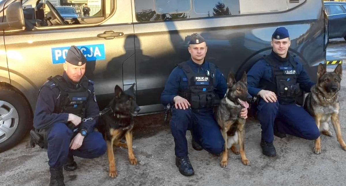 Zdjęcie policjantów z psami na tle nowego pojazdu