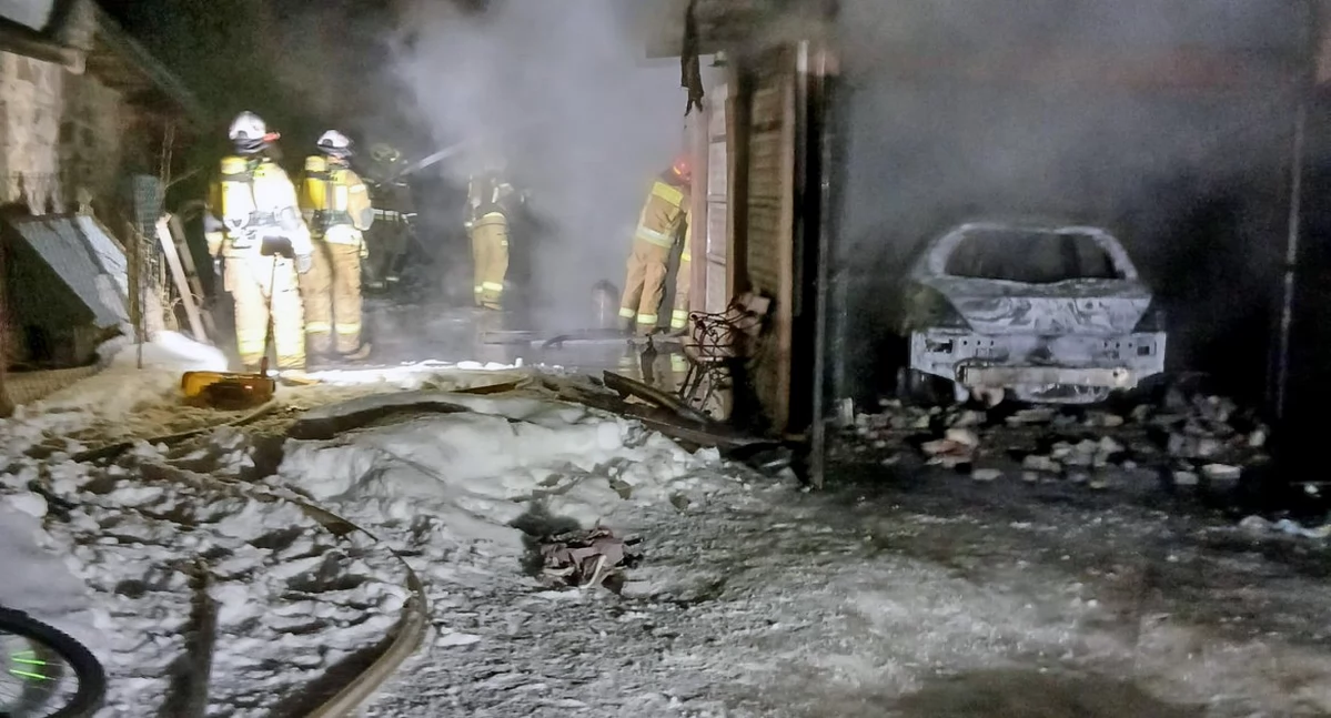 Zdjęcie strażaków gaszących ogień. Po prawej wrak Peugeota