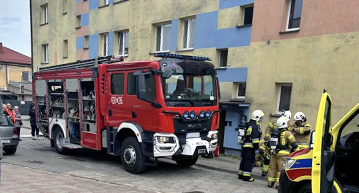 Zdjęcie strażaków i samochodu strażackiego przed blokiem w Końskich