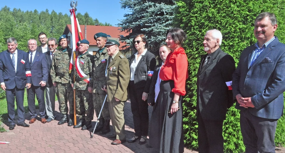 Zdjęcie pod pamiątkowa tablicą, gdzie złożono kwiaty a uczestnicy w zadumie rozpamiętywali czas wojny